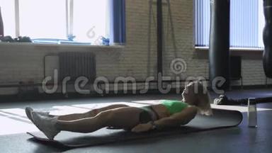 运动垫上的女运动员在健身房做腹肌锻炼。 肌肉女运动员做腹肌锻炼。
